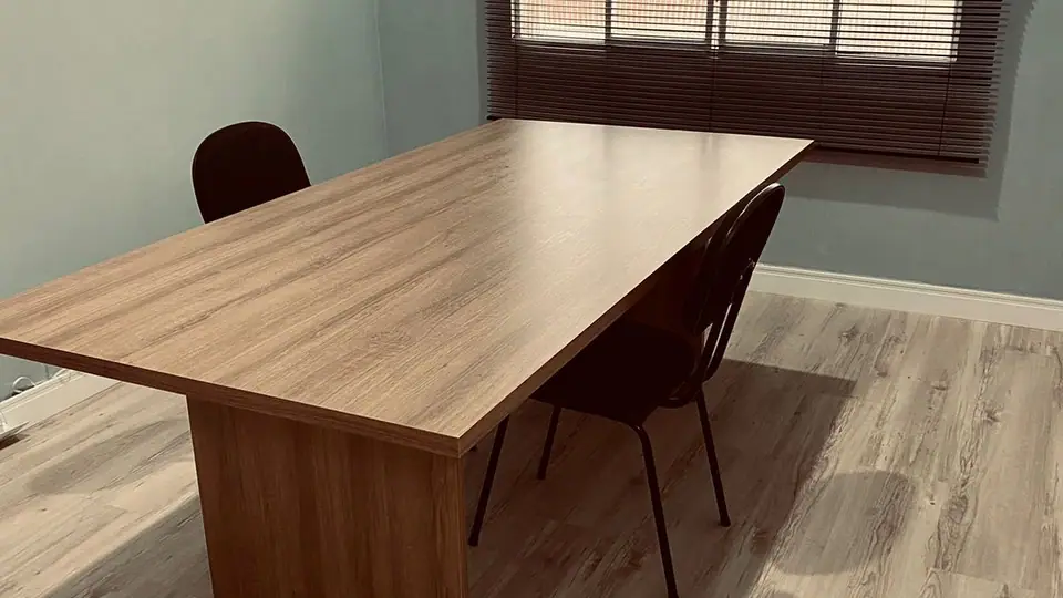 Sala de reunião do escritório, com mesa de madeira e cadeiras pretas
